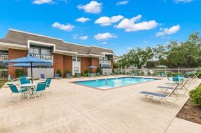 River Ridge apartment for rent - A pool area with chairs and a building in the background.