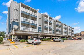 Metairie apartment for rent - A parking lot in front of a multi-story apartment building.