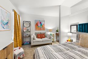 Metairie apartment for rent - A bedroom with a bed, a couch, a chair, and a painting on the wall.