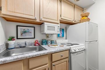 Metairie apartment for rent - A kitchen with wooden cabinets and a white refrigerator.