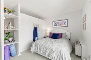 Metairie apartment for rent - A white bedroom with a white bed and a white shelf with plants on it.