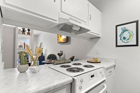 Metairie apartment for rent - A white kitchen with a stove top oven and a fridge.