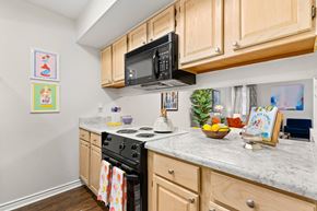 Metairie apartment for rent - A kitchen with wooden cabinets and a black microwave above the stove.