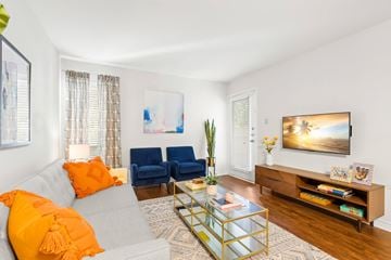 Metairie apartment for rent - A living room with a grey couch, a blue chair, a glass coffee table, and a painting on the wall.