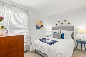Metairie apartment for rent - A bedroom with a white bed and a wooden dresser.