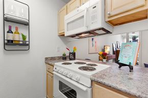 Metairie apartment for rent - A kitchen with a white stove top oven and a white microwave above it.