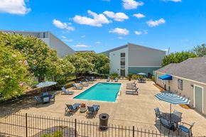 Metairie apartment for rent - A pool surrounded by chairs and umbrellas.