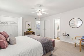 Metairie apartment for rent - A bedroom with a bed, a chair, and a mirror on the wall.