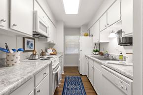 Metairie apartment for rent - A kitchen with white cabinets and a marble countertop.