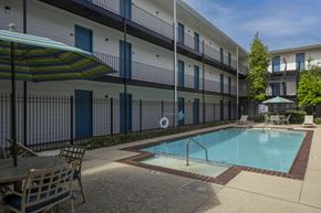 Metairie apartment for rent - A pool area with a table and chairs and umbrellas.