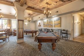 Fresno apartment for rent - A room with a pool table and a painting of a landscape on the wall.