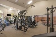 Fresno apartment for rent - A spacious gym with a variety of equipment including treadmills, weights, and a ceiling fan.