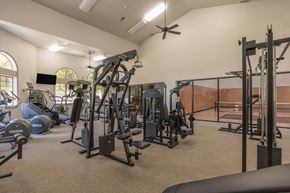 Fresno apartment for rent - A spacious gym with a variety of equipment including treadmills, weights, and a ceiling fan.