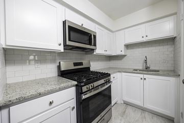 El Paso apartment for rent - a kitchen with white cabinets and a stove and a microwave