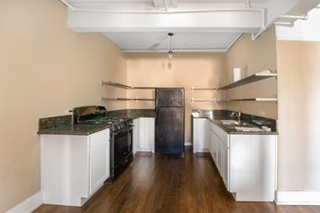El Paso apartment for rent - A kitchen with a black refrigerator and white cabinets.