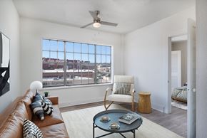 El Paso apartment for rent - A living room with a brown leather couch, a white chair, a coffee table, and a ceiling fan.