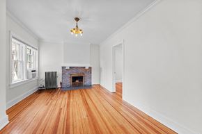Denver apartment for rent - an empty living room with a brick fireplace and wooden floors