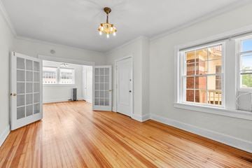 Denver apartment for rent - a living room with a hardwood floor and a door to a hallway with windows
