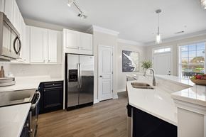 Cary townhouse for rent - A modern kitchen with white cabinets and a black refrigerator.