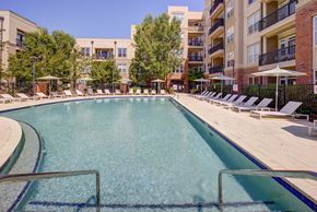 Cary townhouse for rent - A large swimming pool surrounded by sun loungers and apartment buildings.