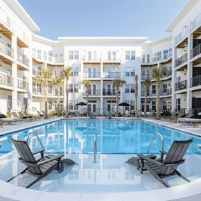 Charleston apartment for rent - A swimming pool with two lounge chairs in front of a white apartment building.
