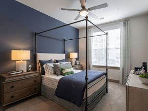 Charleston apartment for rent - A bedroom with a four-poster bed, a ceiling fan, and a nightstand with a lamp.
