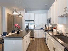 Charleston apartment for rent - A kitchen with white cabinets and a black countertop.