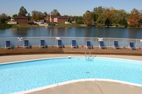 Indianapolis apartment for rent - a swimming pool with blue chairs next to a body of water
