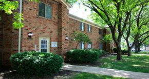 Indianapolis apartment for rent - the side of a brick building with trees and a sidewalk