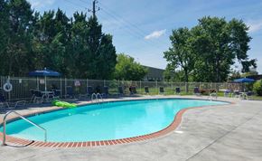 Indianapolis apartment for rent - a resort style pool with chairs and umbrellas next to a fence