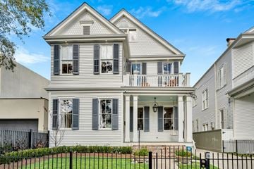 New Orleans apartment for rent - A two-story house with a front porch and a black fence.
