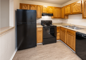 Metairie apartment for rent - A black refrigerator is in a kitchen with wooden cabinets.