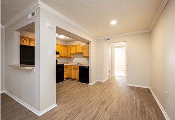 Metairie apartment for rent - A kitchen with wooden cabinets and a black fridge.