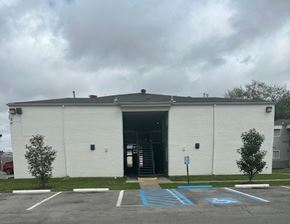 Gretna apartment for rent - A white building with a grey roof and a parking lot in front.