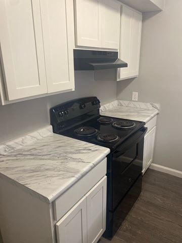 Baton Rouge apartment for rent - A kitchen with a black stove top oven and white cabinets.