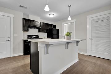 Lansing apartment for rent - A kitchen with black cabinets and a white island.