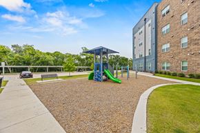 Garland apartment for rent - A playground with a blue slide and a green slide in front of a building.