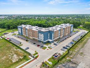 Garland apartment for rent - A large building with a parking lot in front of it.
