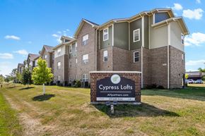 Cedar Rapids apartment for rent - A sign for Cypress Lofts is in front of a building with a grassy area in the foreground.