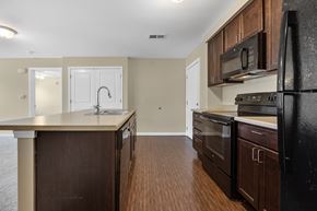 Cedar Rapids apartment for rent - A kitchen with dark wood cabinets and a black refrigerator.