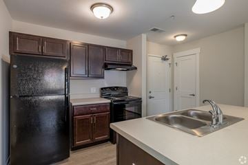 Jackson apartment for rent - A kitchen with a black refrigerator and brown cabinets.
