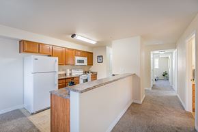 West Richland apartment for rent - a long kitchen with white appliances and a granite counter top  at Quail Springs, West Richland, WA, 99353