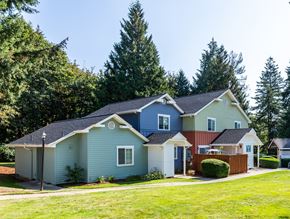 Poulsbo townhouse for rent - a blue house and a red and blue house with a yard and trees at Woodcreek, Poulsbo, WA