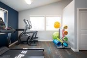 Post Falls apartment for rent - Fitness center with white walls and one dark blue accent wall. An elliptical machine, treadmill and stand with exercise balls and yoga mats are visible.at North Pointe, Post Falls