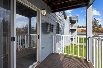 A balcony with a sliding glass door leading to a deck at the overlook apartments in post falls, id. .