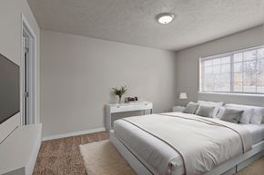 Post Falls apartment for rent - Staged bedroom at The Overlook Apartments in Post Falls featuring a large bed, nightstand, and bright natural light.