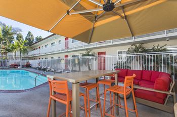A patio with a table and chairs next to a pool 