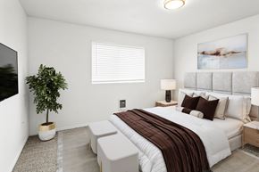 Post Falls apartment for rent - a large bedroom with white walls, a window on back wall and carpet. Staged with a queen-sized bed, side tables, a plant and a flat screen TV.at North Pointe, Idaho, 83854