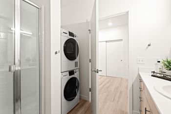 A white laundry room with a washer and dryer and a glass door