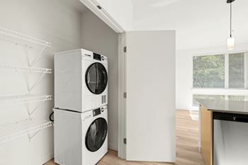 Large kitchen pantry with white metal shelves on left and full-size washer and dryer on right side. At the duo apartments in university place.